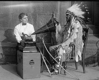 Photograph shows Frances Densmore recording Native American songs sung by Mountain Chief (Sioux). 