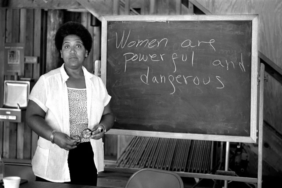 Audre Lorde by a blackboard that says "women are powerful and dangerous"